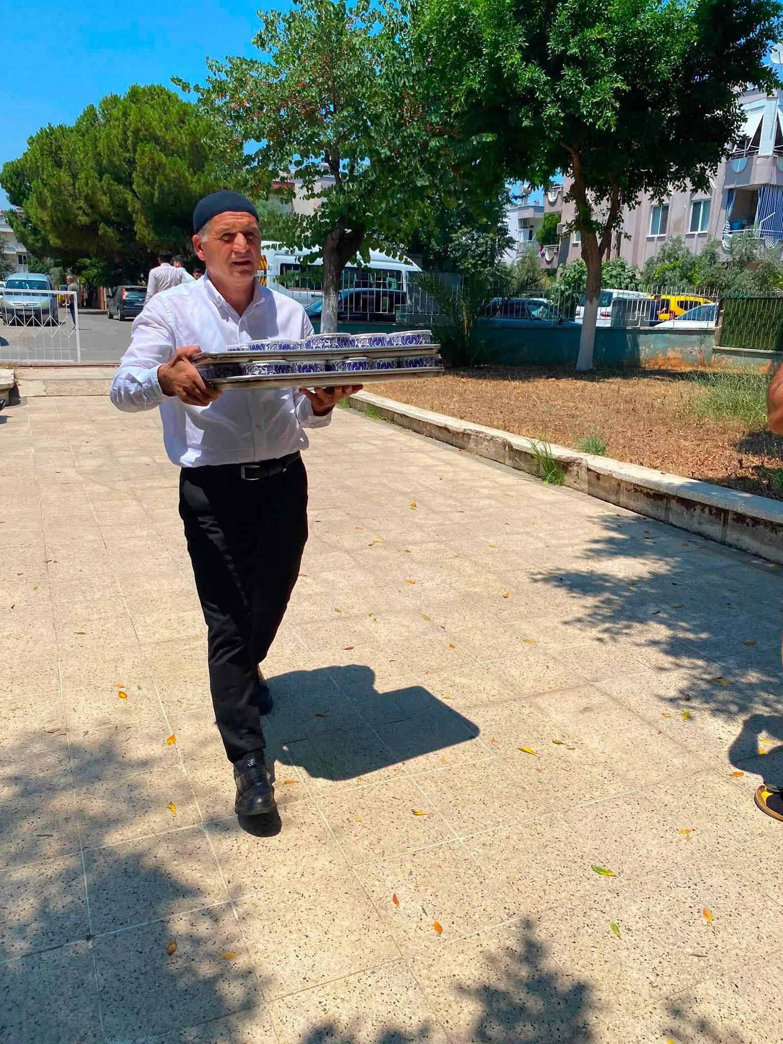 Görevlinin aşure tepsilerini dağıtım noktasına taşıması